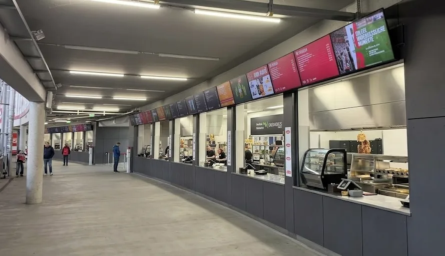 Kantinengang in einem Stadion mit Menüboards über den Ausgabestellen
